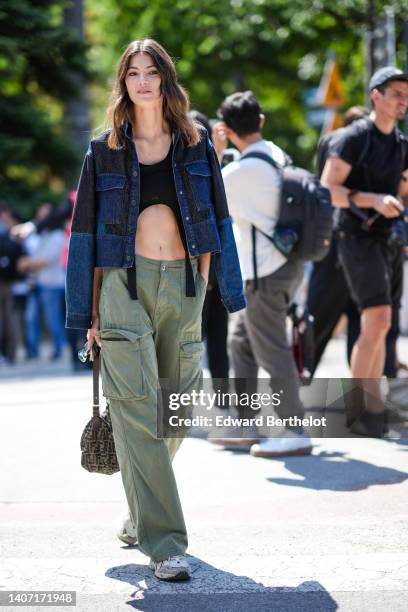 Guest wears a navy blue and black denim jacket, a black cropped top, khaki cargo pants, a brown and black FF monogram print pattern handbag from...