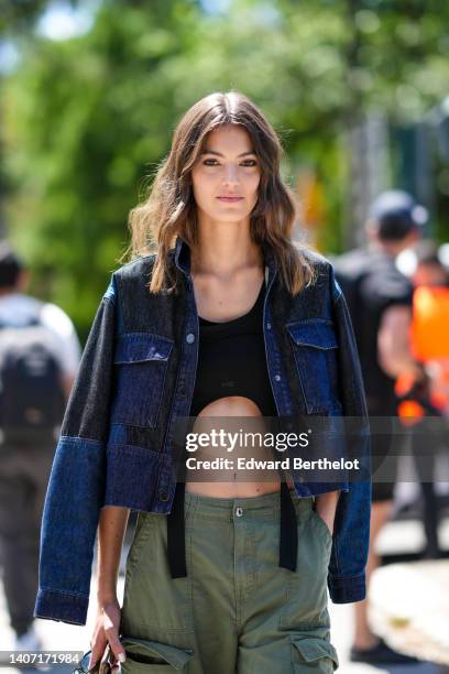 Guest wears a navy blue and black denim jacket, a black cropped top, khaki cargo pants, outside Chanel, during Paris Fashion Week - Haute Couture...