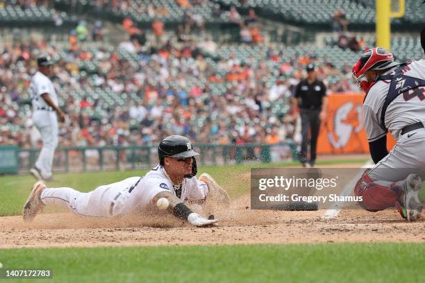 Javier Baez of the Detroit Tigers slides into home plate past Sandy Leon of the Cleveland Guardians to score a fifth inning run at Comerica Park on...