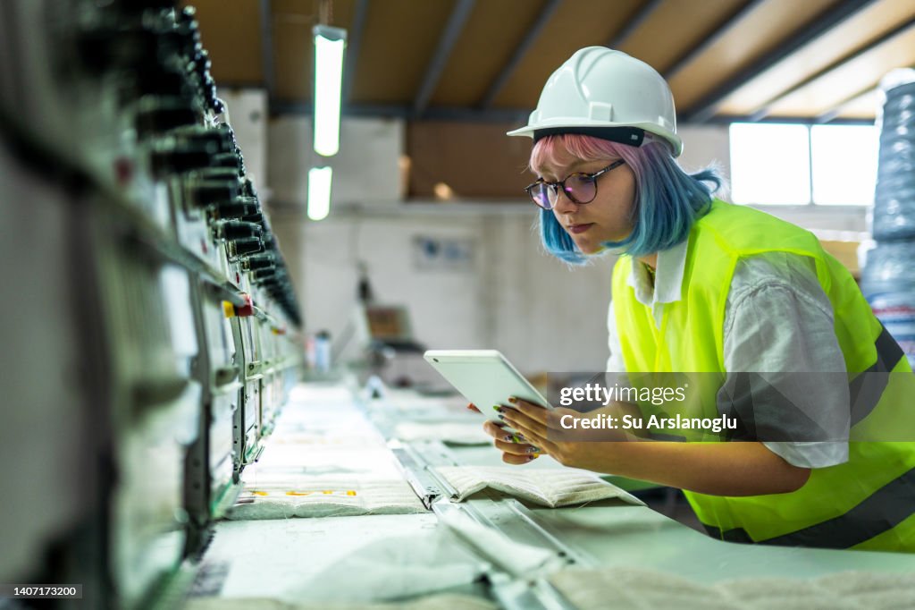 Young female engineer working with manufacturing equipment in a factory