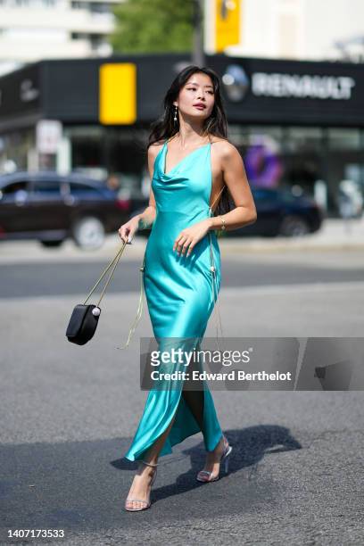 Caroline Hu wears gold and pearl earrings, a gold with white pearls bracelet from Van Cleef and Arpels, a blue / mint green V-neck / silk long slit...