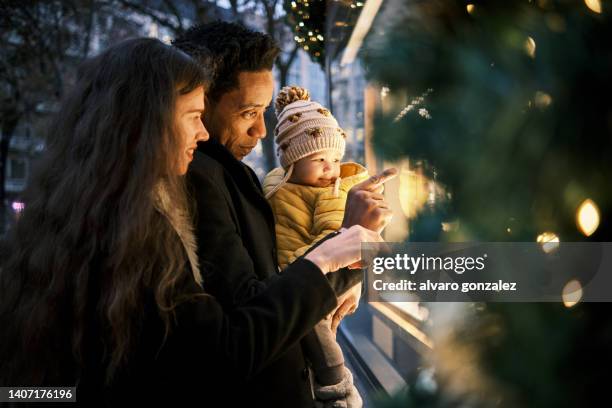 happy interracial family enjoying doing christmas shopping together in the city. - noel sapin stock-fotos und bilder