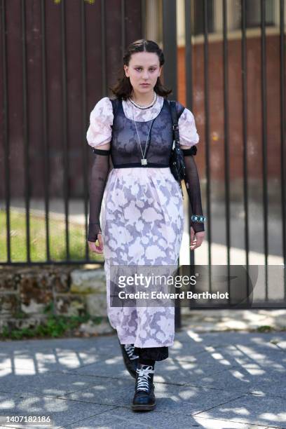 Guest wears white pearls necklaces, a silver chain long necklace, a white flower print pattern puffy sleeves long dress, a black fishnet cropped...