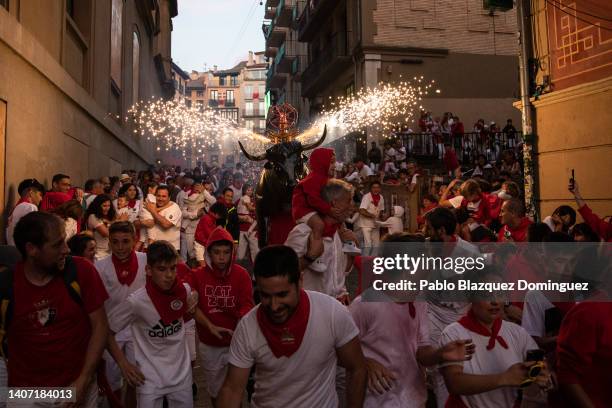 People and children are chased by the 'Toro de Fuego' as it runs through the streets during the opening day or 'Chupinazo' of the San Fermin Running...