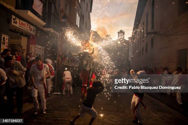 People and children are chased by the 'Toro de Fuego' as it runs through the streets during the opening day or 'Chupinazo' of the San Fermin Running...