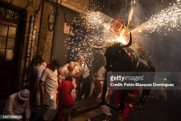 People and children are chased by the 'Toro de Fuego' as it runs through the streets during the opening day or 'Chupinazo' of the San Fermin Running...