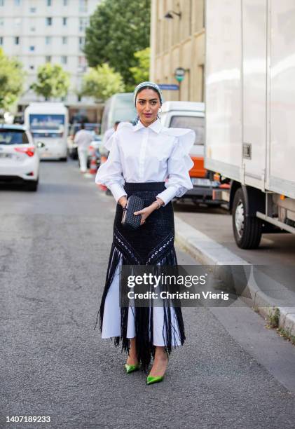 Guest is seen wearing white blouse, black skirt with fringes, white wide pants, heels, head scarf outside Alexandre Vauthier Paris Fashion Week -...