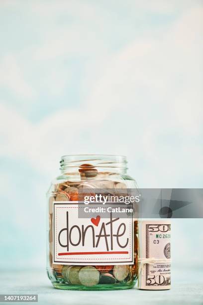 donation jar filled with american currency and a wad of fifty dollar bills against a bright background with lots of copy space - money donation stock pictures, royalty-free photos & images