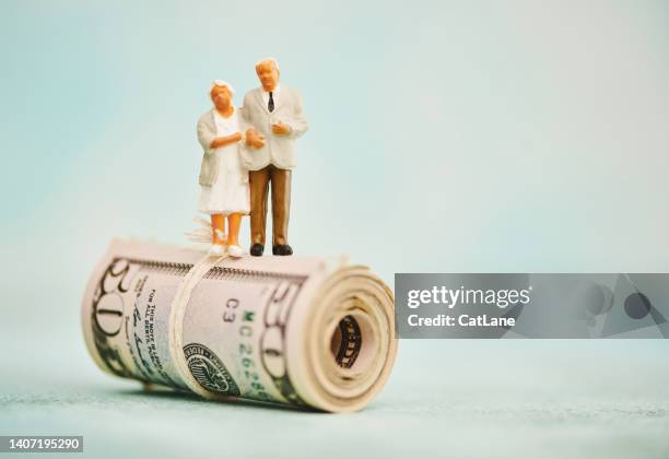 miniature figures of elderly couple standing on top of a wad of fifty dollar bills - figurine bildbanksfoton och bilder