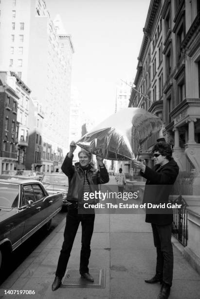 American artist, film director, and producer Andy Warhol and American musician, singer, songwriter, and poet Lou Reed , hold one of Warhol's iconic...