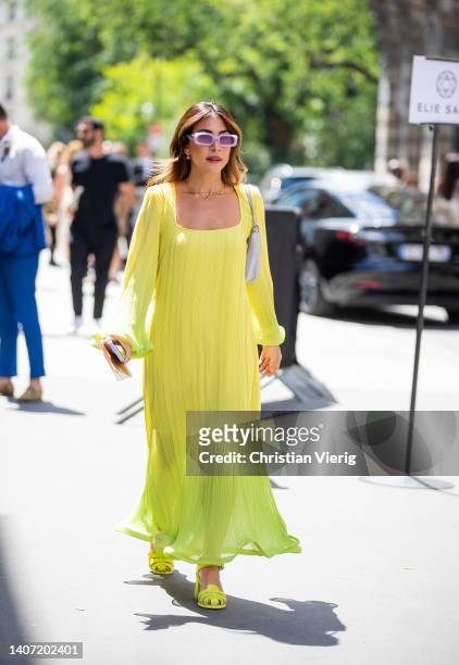 Guest is seen wearing yellow dress with long sleeves, shoes, grey bag outside Elie Saab during Paris Fashion Week - Haute Couture Fall Winter 2022...