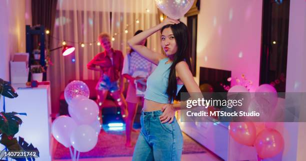 young asian female friends tiktok created her walking fashion shows video by smartphone having fun at colorful house party at night. - collection launch party stock pictures, royalty-free photos & images