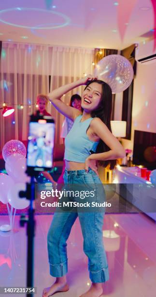 young asian female friends tiktok created her walking fashion shows video by smartphone having fun at colorful house party at night. - kids fashion show stock pictures, royalty-free photos & images