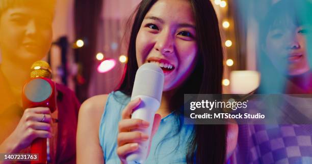 close up of young asian female friends singing karaoke having fun at colorful house party at night. - asian rapper stock pictures, royalty-free photos & images