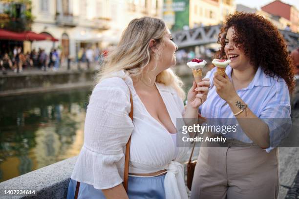 two women enjoying summer holiday and eating an ice cream - gelato stock pictures, royalty-free photos & images