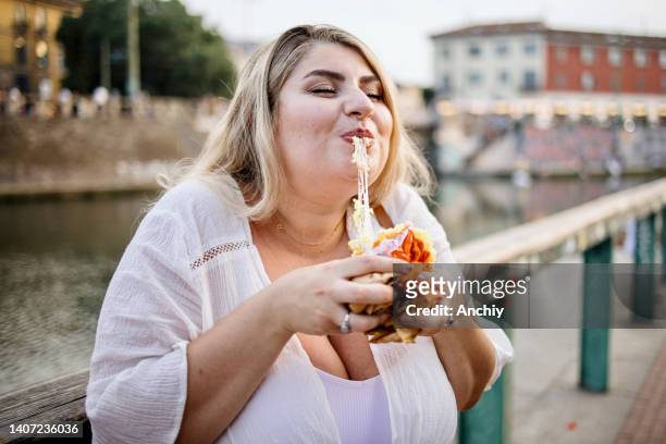 close up of a woman eating and enjoying fast food outside - calzone stock pictures, royalty-free photos & images