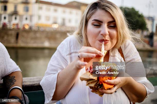 Close up of a woman eating and enjoying fast food outside