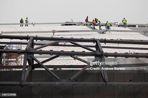 Construction workers work on the roof of the Barclay Center, a sports arena and future home of the the National Basketball Association's New Jersey...