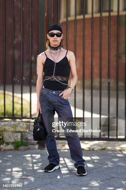 Guest wears a black scarf as a hat, black sunglasses, a black shiny leather with large embroidered ring necklace, a black V-neck / tank-top and lace...