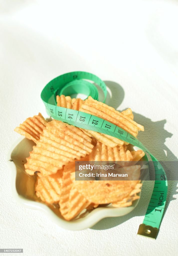 Diet and snack illustration - potato chips and measuring ribbon meter
