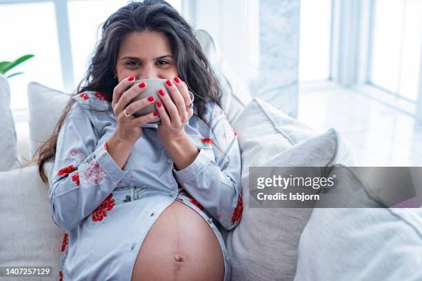 pregnant woman relaxing whit cup of tea at home - koffiekoek stockfoto's en -beelden