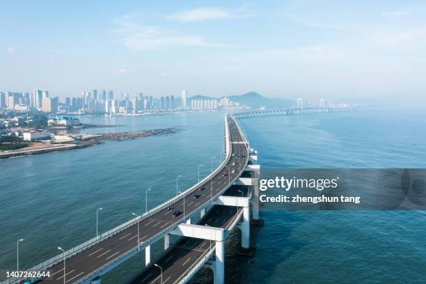 aerial view of cross-sea bridge with background of city skyline. - cable stayed bridge stock-fotos und bilder