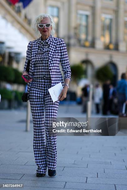 Guest wears white sunglasses, a black and white houndstooth print pattern shirt, a black black and white houndstooth print pattern jacket, matching...