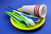 Disposable tableware in a pile lie on a blue background.