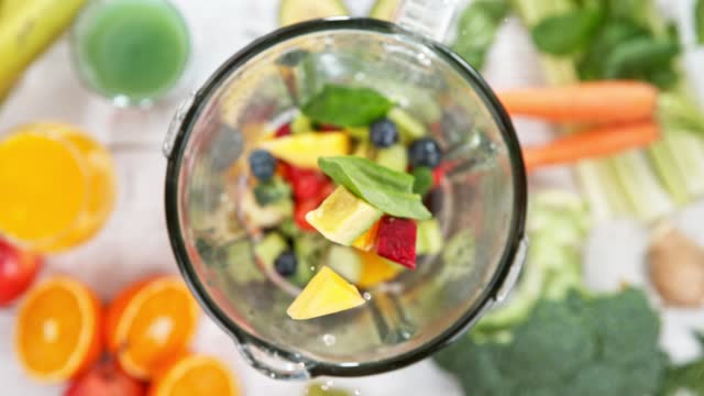 Super slow motion of falling pieces of fruit and vegetable into blender.
