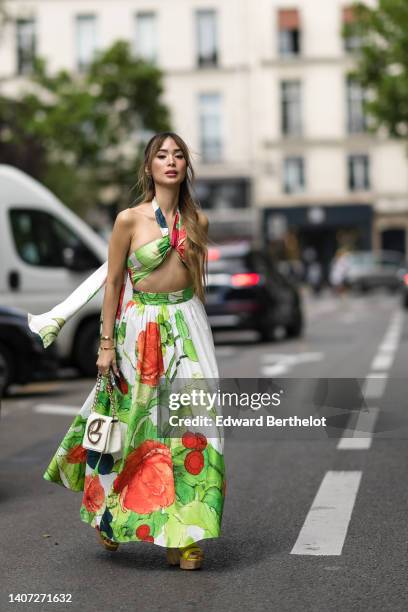 Heart Evangelista wears gold earring, a green / white / red flower print pattern halter-neck / cropped top, a matching green / white / red flower...