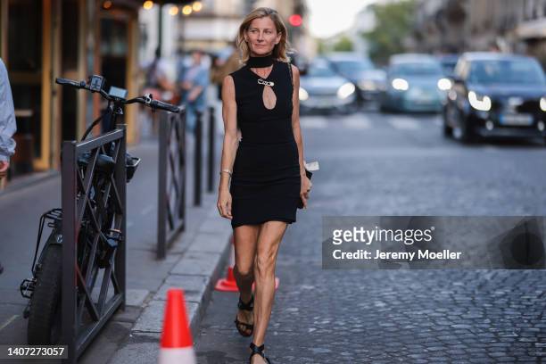 Guest seen wearing a black high neck/cut-outs short dress, a gold brooch from Versace by Fendi, silver diamonds bracelet, a black leather Chanel bag...