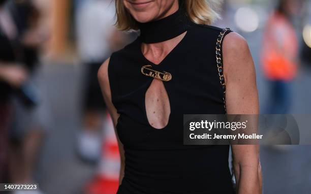 Guest seen wearing a black high neck/cut-outs short dress and a gold brooch from Versace by Fendi, outside the Giorgio Armani Prive show, during...