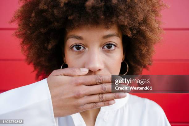 young woman covering mouth with hand - hands covering mouth stockfoto's en -beelden