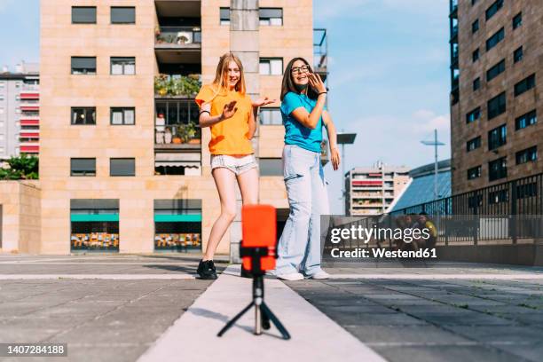 happy girls dancing filming through mobile phone on sunny day - children dancing outside stockfoto's en -beelden