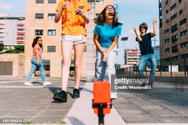 cheerful girl with friends having fun vlogging on sunny day - preteen foto e immagini stock