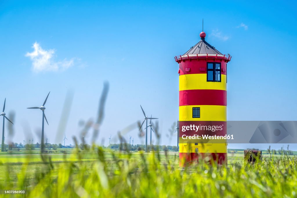 Germany, Lower Saxony, Krummhorn, Pilsum Lighthouse in spring with wind farm in background