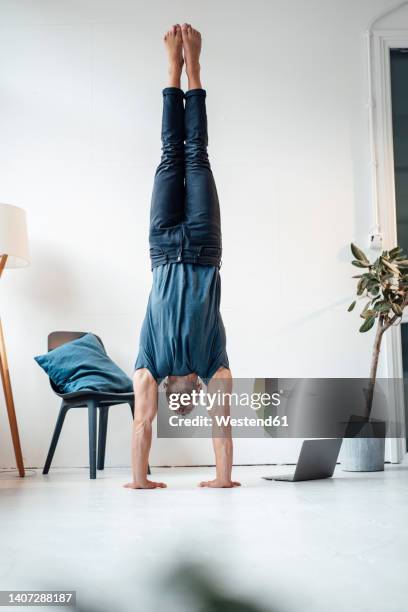 man doing handstand by chair in front of wall at home - bodyweight training stock pictures, royalty-free photos & images