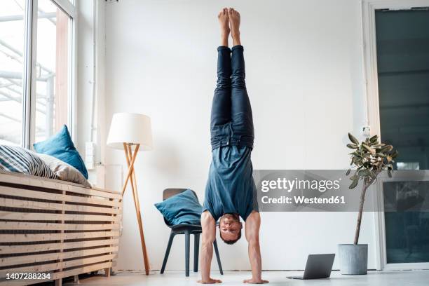 man practicing handstand in front of wall at home - it's all easy foto e immagini stock