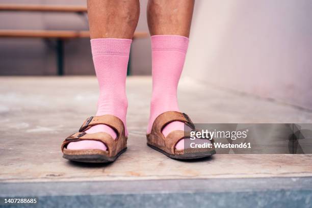 legs of man standing on floor wearing pink socks and sandals - sandales photos et images de collection