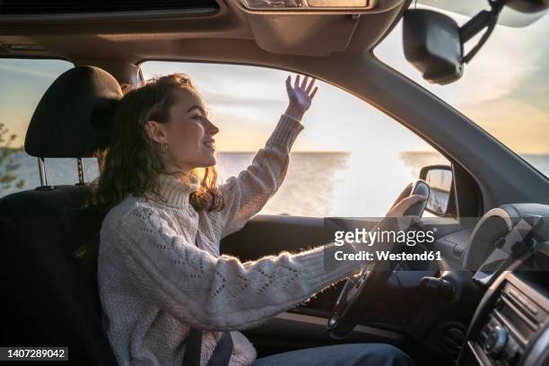 happy young woman sitting on driver's seat in car - driver's seat stock-fotos und bilder