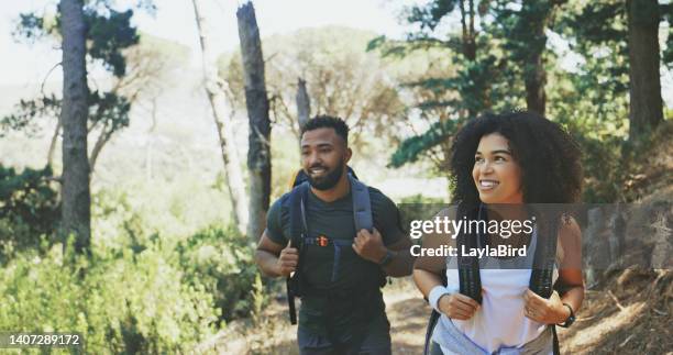 couple hiking in mountains. husband and wife backpacking through the wilderness on vacation. boyfriend and girlfriend on an adventurous hike in nature. man and woman walking in a forest on holiday - backpacker road stockfoto's en -beelden