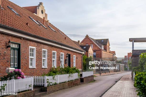 germany, lower saxony, juist, empty street stretching in front of brick town houses - ostfriesiska öarna bildbanksfoton och bilder