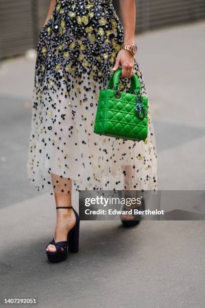 Guest wears a white with embroidered black / yellow / navy blue sequined print pattern V-neck / puffy short sleeves / midi dress, a green shiny...