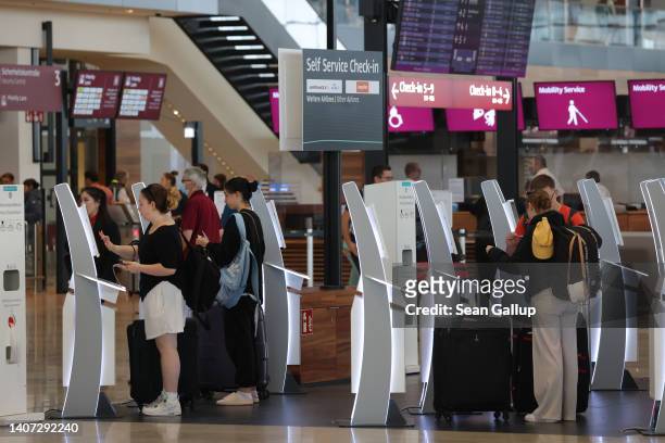 Passengers do a self-service check in at Terminal 1 at Berlin Brandenburg Airport on the first day of the local summer school vacation on July 07,...