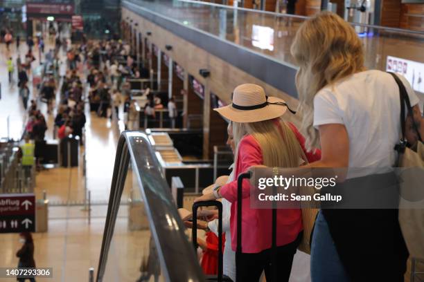 Women with suitcases descend an escalator before going through security for departures at Terminal 1 at Berlin Brandenburg Airport on the first day...