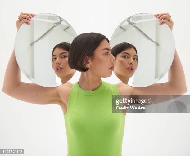 woman looking at reflection in two mirrors - beeldmanipulatie stockfoto's en -beelden