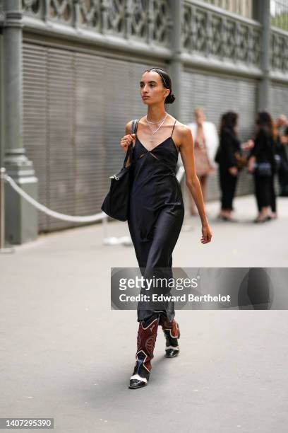 Guest wears silver chain necklaces, a black cut-out V-neck silk long dress, a black fabric shoulder bag from Longchamp, black shiny leather crocodile...