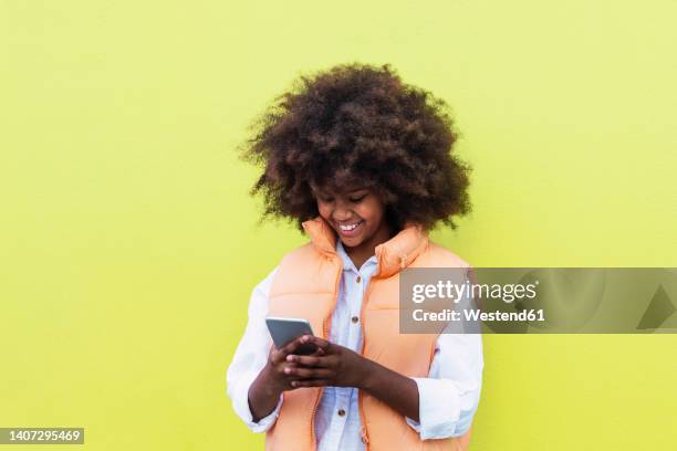 happy girl using smart phone against yellow background - only girls stock pictures, royalty-free photos & images