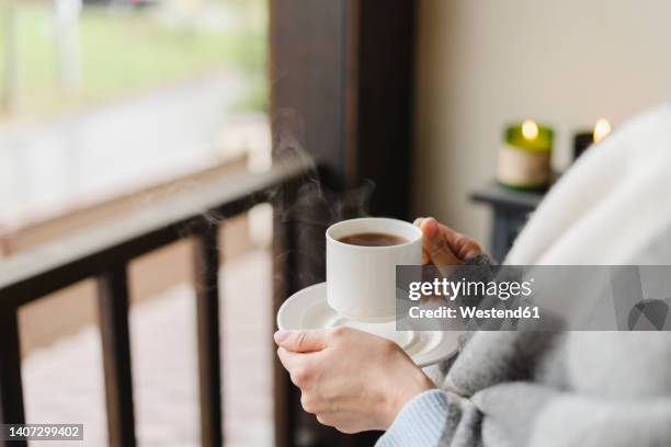 hands of woman holding coffee cup and saucer at home - cup saucer stock pictures, royalty-free photos & images