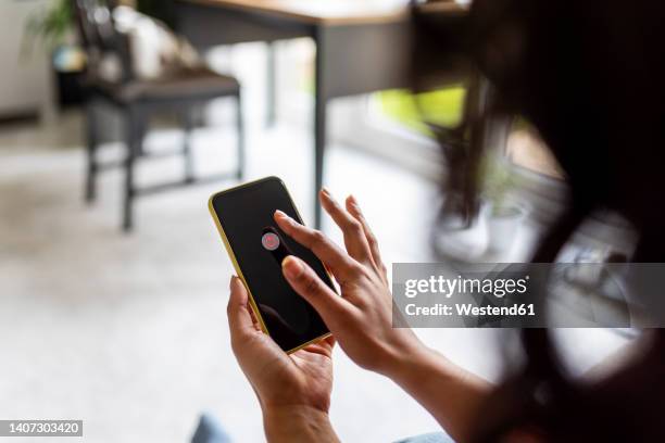 woman turning off smart phone at home - turning on or off stockfoto's en -beelden